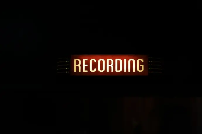 a red recording sign lit up in the dark